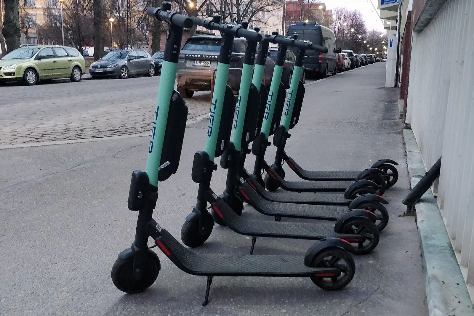 Rida jagatud elektritõukerattaid tänava ääres.
